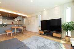 LDKのテーマは『寝転がれる空間』。「のんびりくつろげるよう、気取りがなくてちょっと上品な雰囲気を目指しました」とご主人。テレビ背面のエコカラットの壁にスポットライトをあて、上質感をアップ。高気密・高断熱＋全熱交換型換気システムで、夏もエアコンをあまり使わず過ごせる。冬はガス温水式床暖房のみで十分に暖か