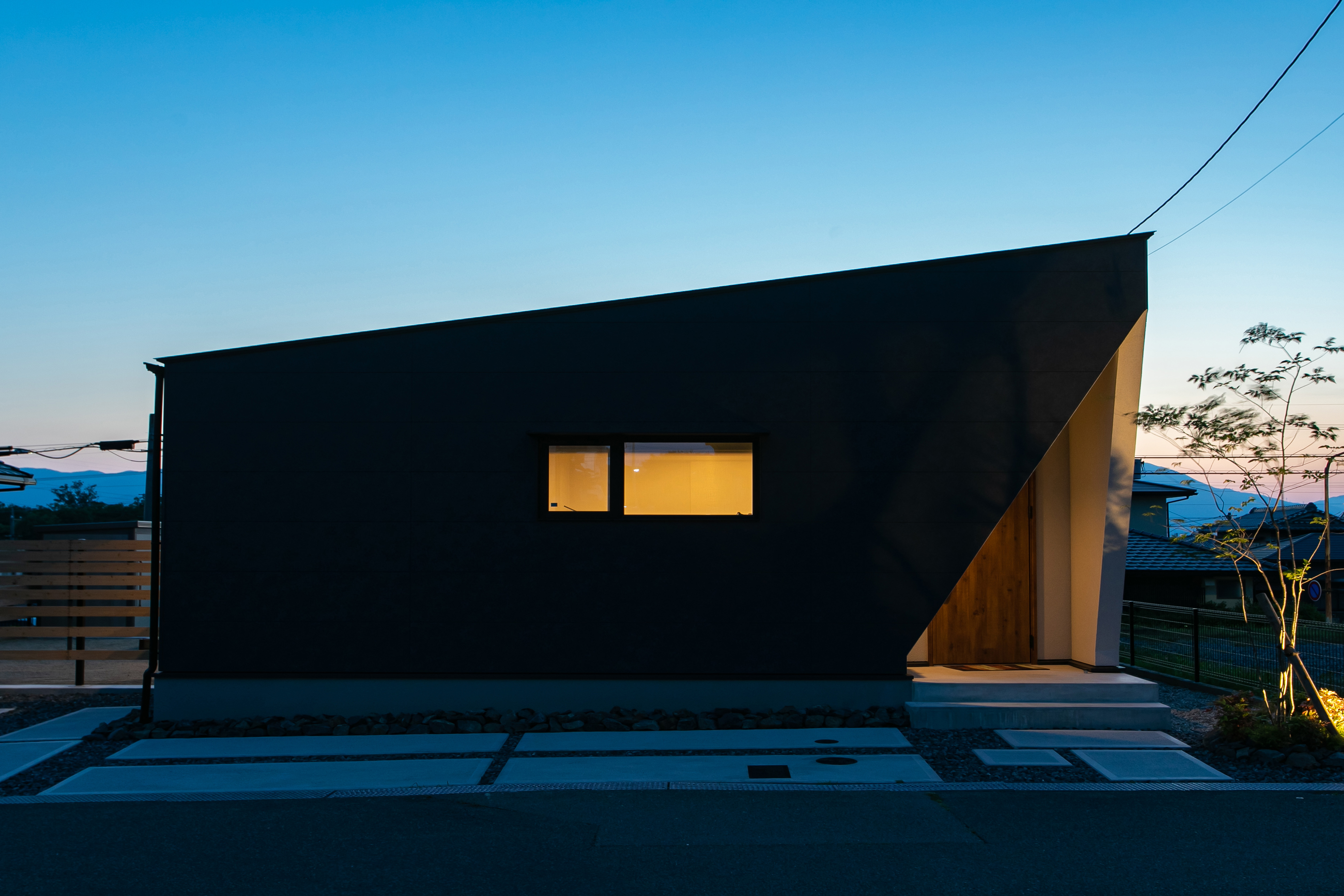 HOME CRAFT｜夜の美しさが際立つシンプルで洗練された建物の外観。控えめなライトが建物の形状を際立たせ、落ち着いた印象を与えている。