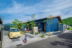 紺色のガルバリウムに植栽がマッチしていて、ゆとりを感じる外観になった。 休日は広いウッドデッキでゆったりとした時間を過ごせそう。