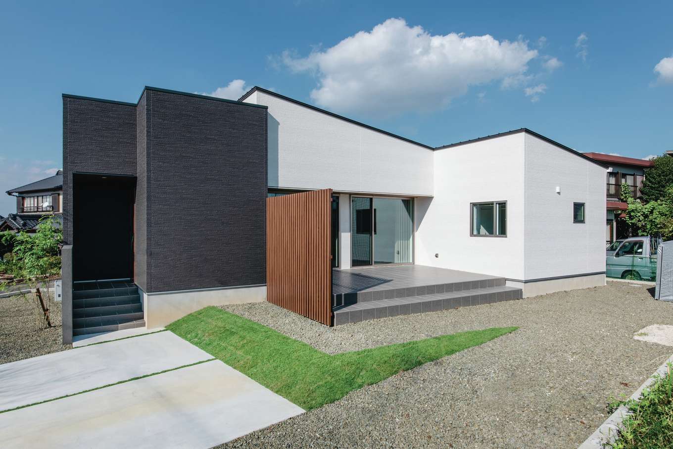 吉川住建【デザイン住宅、夫婦で暮らす、平屋】タイルデッキを挟んでコの字型にレイアウトしたスタイリッシュな外観。広いテラスと庭は、ご主人が洗車をするときにも重宝する
