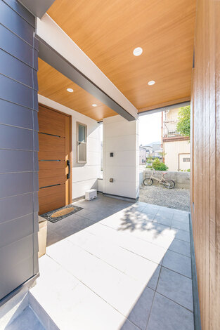 広々としたピロティタイプの玄関ポーチは、雨の日の出入りも苦にならない。木質の軒天井で温かみをプラス