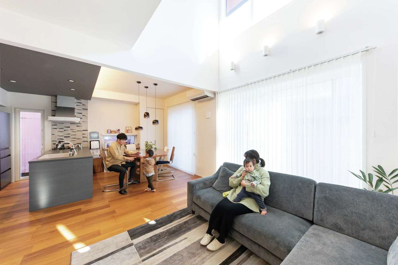 静鉄ホームズ【デザイン住宅、間取り、インテリア】取材で訪れた真冬の寒い日でも、吹き抜けから降り注ぐ暖かな光に包まれていたLDK。高天井に合わせた大きな窓の向こうにはウッドデッキも。夏は子どもプールやプチBBQを楽しんだそう