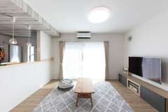 親世帯のLDK。窓の外にはタイルデッキと庭が続き、子世帯のLDKとやわらかくつながる。普段は背中側にレイアウトされている寝室との間を開き、大きな空間として使用している