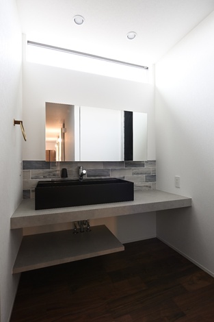 モダンなデザインの洗面スペースである。シンプルな鏡と収納しやすいキャビネットが特徴である。落ち着いた雰囲気が魅力的で、洗面台周りの空間が広く感じられる。