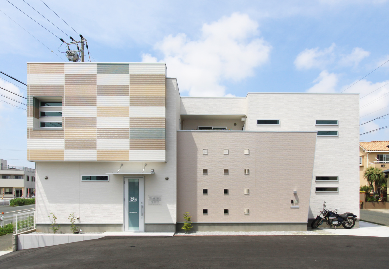 丸昇彦坂建設【デザイン住宅、間取り、インテリア】ユニークな色使いが目を引く外観。生活感を隠すために、家族用の玄関や2階ベランダは飾り壁で覆っている