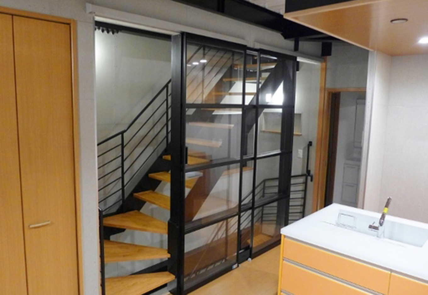 建築システム（狭小住宅専門店）【デザイン住宅、ガレージ、鉄骨鉄筋コンクリート構造】リビングに造ったスケルトン型の階段はスライド式のアクリル製パネルで仕切り視線に広がりをもたせた