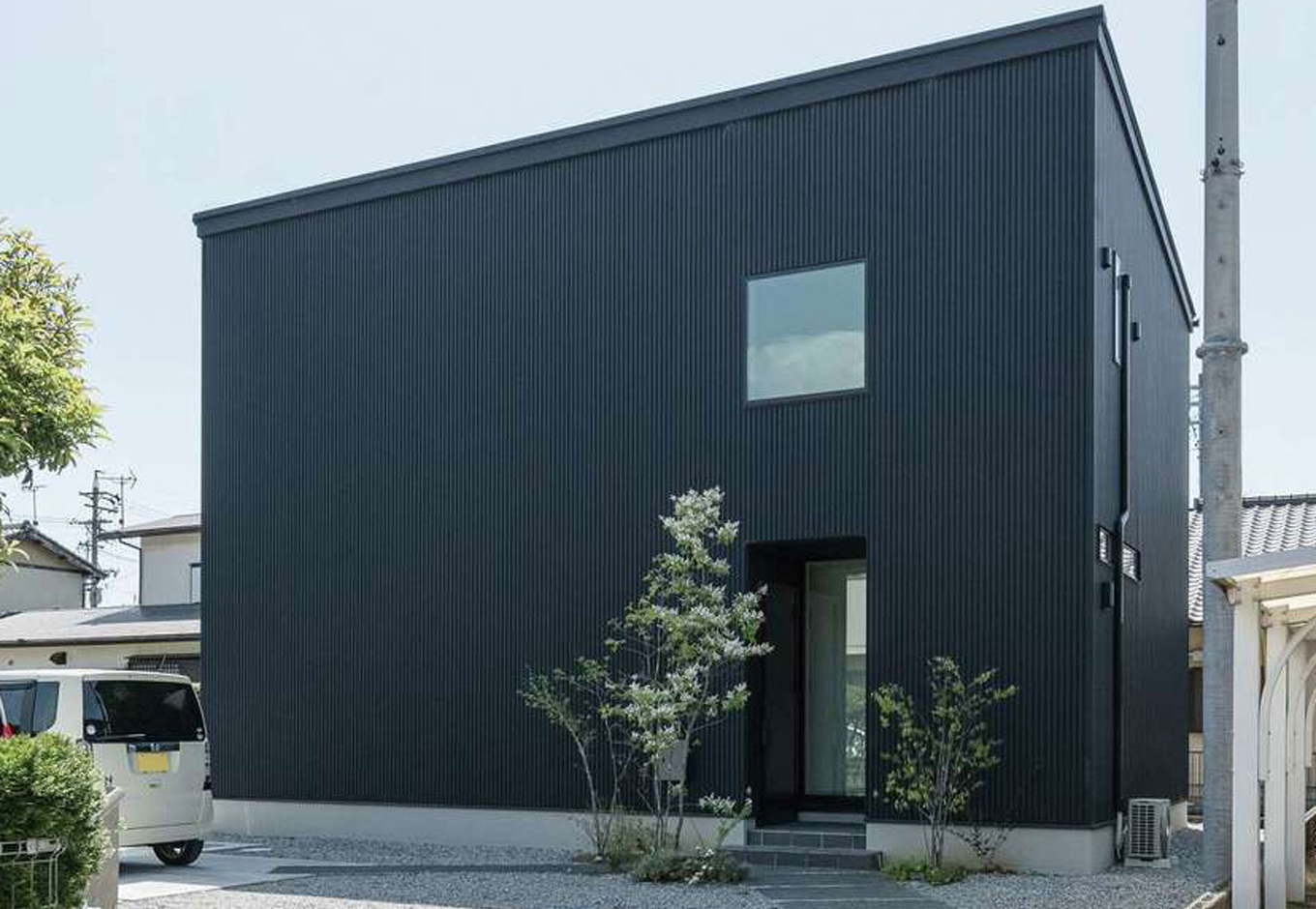 HAPPY HOUSE（山田工務店）【1000万円台、デザイン住宅、子育て】土地探しも一緒に。静かな住宅地の奥まった場所にある土地を気に入った。正面は開口部を減らし、デザイン性とプライバシーの確保を両立。玄関横の窓は担当の藤田さんの提案で、玄関に明るさをもたらしつつ、帰宅の際はあたたかな光が迎えてくれる