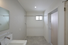 3帖の洗面脱衣 兼 ランドリースペース。シーツや洗濯物、お風呂上がりのバスタオルも広々干せるパイプを、身長に合わせて設置。実用的で無駄のない快適空間。