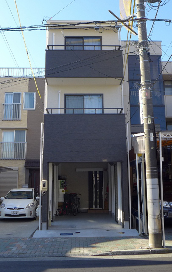 建築システム（狭小住宅専門店）【1000万円台、狭小住宅、ガレージ】外壁はダークブラウンとミルキーホワイトの２色使用。１階はビルトイン式ガレージに。間口が細いスリムな３階ての為、上下に使い分けたツートンカラーで見た目の安定感が増た
