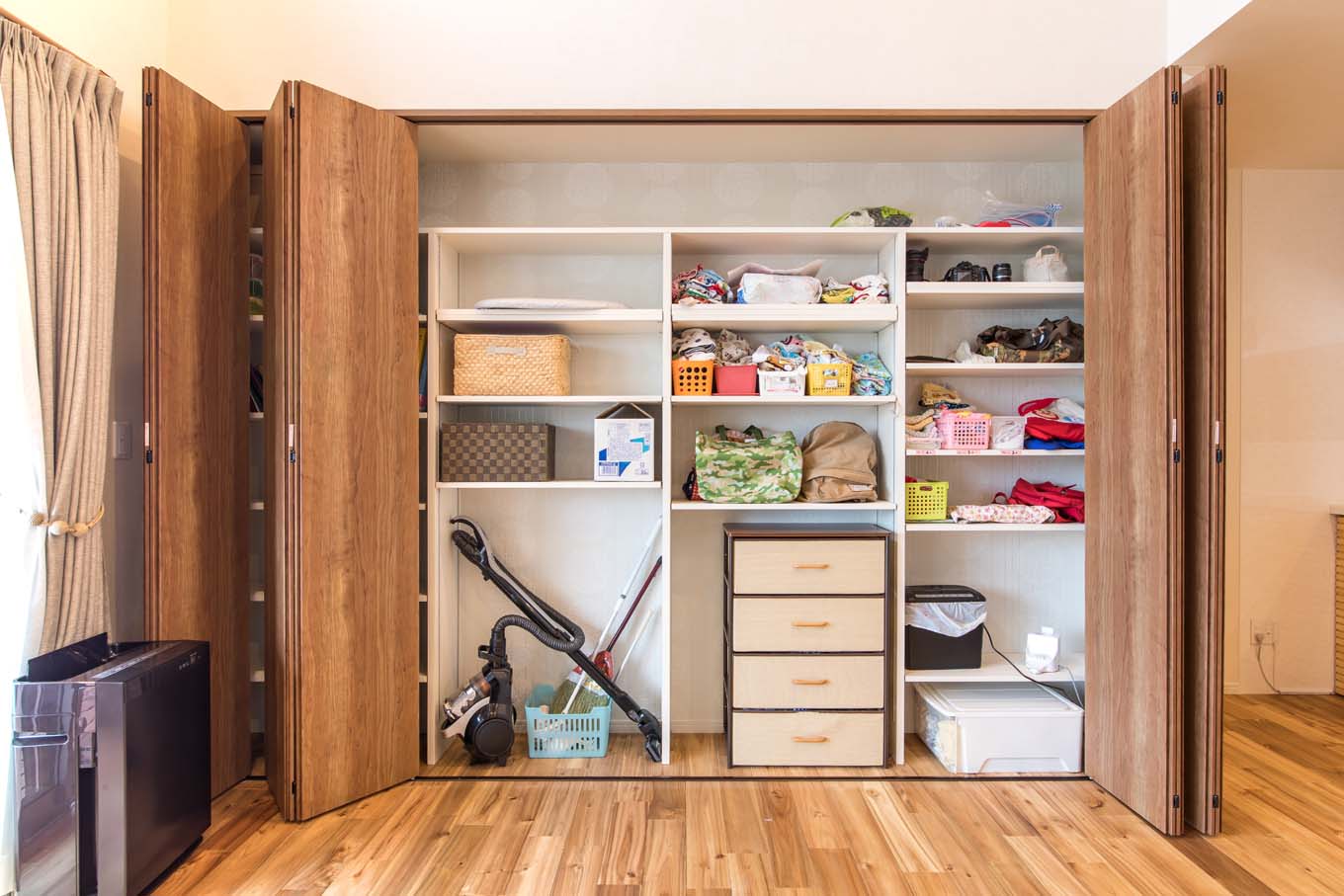 KOUBOU STYLE 建築工房相良（FPの家）【デザイン住宅、収納力、平屋】壁一面に設けたリビングクローゼット。中は可動棚になっているので、収納の目的に合わせて変更可能。折れ戸はそのまま左右にスライドできるので、どの位置のものも取り出しやすい