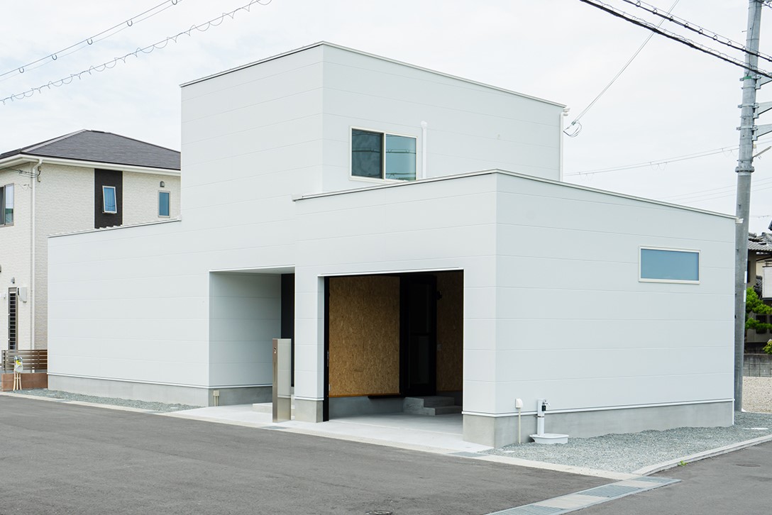 ETERNITY（エタニティ)　SIMPLE NOTE 浜松東【デザイン住宅、建築家、ガレージ】正面から見る外観は、極限まで装飾を削ぎ落としたシンプルなフォルム。右側に車用のビルトインガレージ、中央には玄関がある