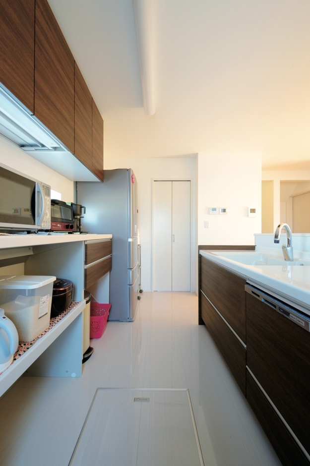 絆家（きずなや）【1000万円台、デザイン住宅、省エネ】ダークブラウンのキッチンがナチュラルカラーの部屋に映える。鏡面仕上げの床は汚れにくくお手入れもラク