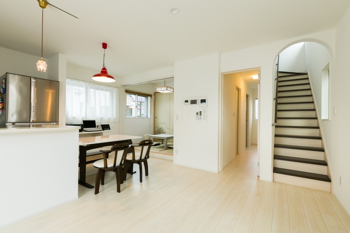 20帖のLDKに入るとまず目に飛び込んでくる赤い照明はお施主様こだわりのものを設置。階段室入口の壁をアーチ型にして柔らかいイメージの空間を演出。踏板をダークブラウンにしたことで、白を基調としたフロアにアクセントをプラス
