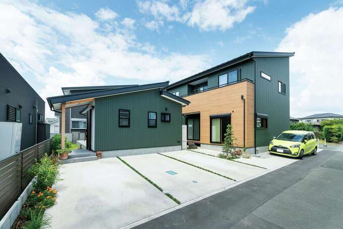 モスグリーンのガルバリウムが青空に映える外観。左の平屋が同時に新築したお姉さまの家