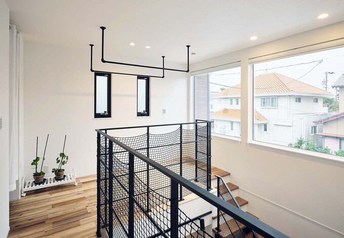 2階のフリースペースには、室内干し用のバーを設置。日当たりがいいので洗濯物がよく乾く。大きな窓からは街並みの風景を見渡すことができ、吹き抜けを通じて1階の家族の様子も感じ取れる