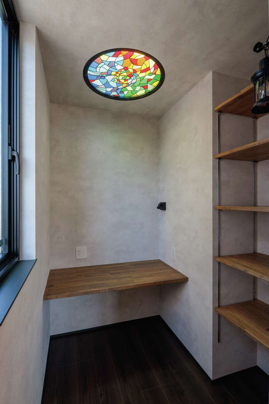 tact design firm【デザイン住宅、省エネ、間取り】主寝室内にあるご主人の書斎。天井にトップライトを設け、さらにハネムーンで訪れたサグラダファミリアをイメージしたオーダーメイドのステンドグラスを組み込ませた。夜になると、外から美しい光が見えるそう。カウンターデスクと大容量の本棚も造作