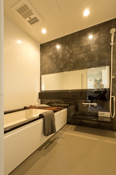 モダンなデザインのバスルーム。大きな鏡とダークトーンの壁がリラックスした雰囲気を演出し、心地よいバスタイムを提供する。