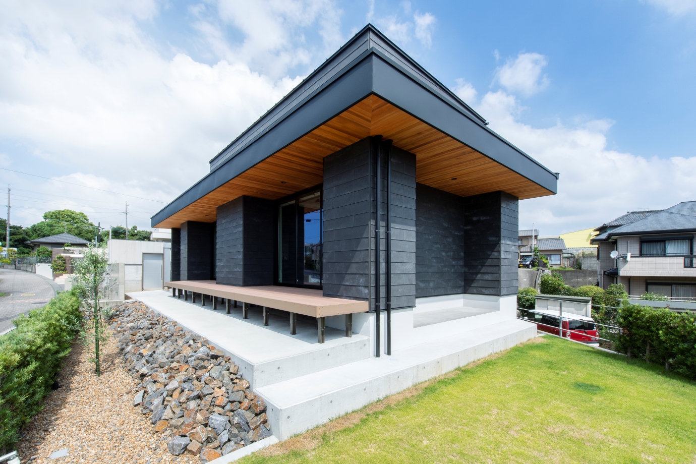リンクホーム【デザイン住宅、間取り、平屋】街中の高台に位置するため、360度どこからでも見てもかっこいいデザインを意識した外観。軒を深く伸ばしたことで夏の直射日光を遮り、太陽高度の低い冬は光をキッチンまで招き入れる。成長しにくいという芝生の選定までこだわり抜いた