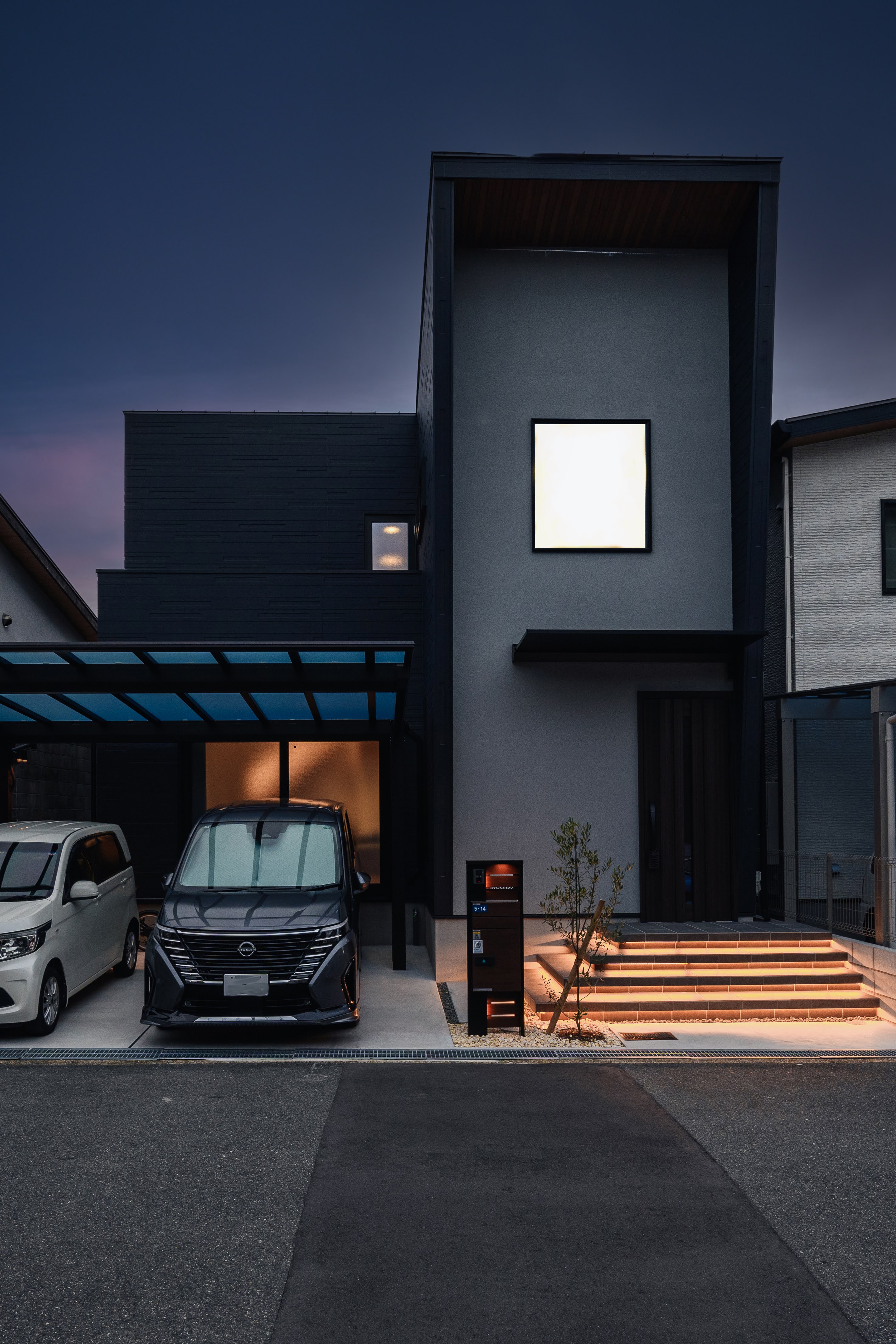 K-rise｜モダンなデザインの外観が特徴的な住宅。シンプルな線とダークな色調が落ち着いた雰囲気を醸し出しており、夜間にはライティングが際立つ印象を与える。
