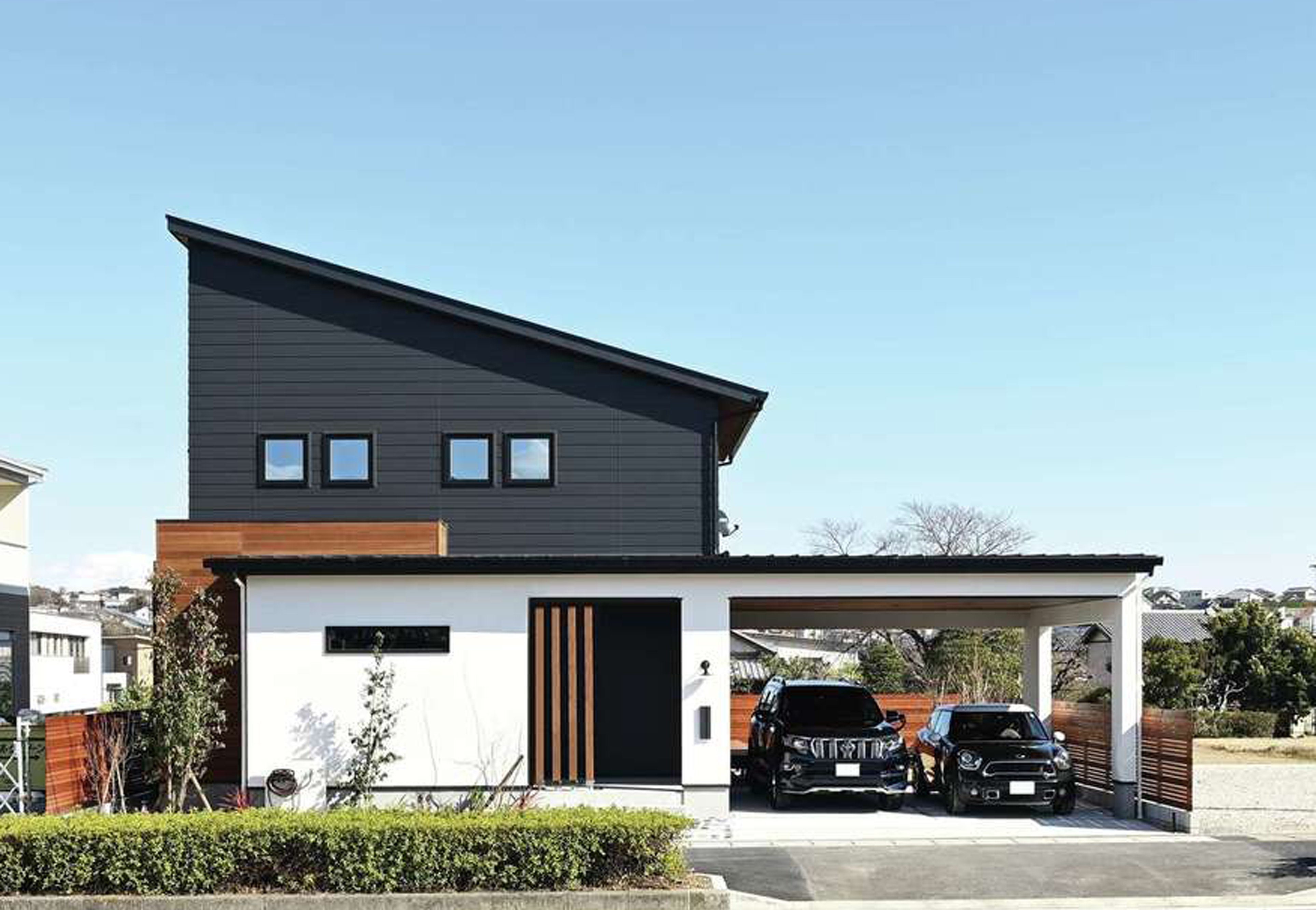Yamaguchi Design 【磐田市見付1853-19・モデルハウス】建物の1階とガレージの屋根が一体化したスタイリッシュな外観デザイン。水平、垂直の美しいラインも計算されている。黒いガルバリウム、白い塗り壁、天然木の異素材がバランス良く調和し、青空にもよく映える。片流れの屋根に7kWの太陽光発電を搭載
