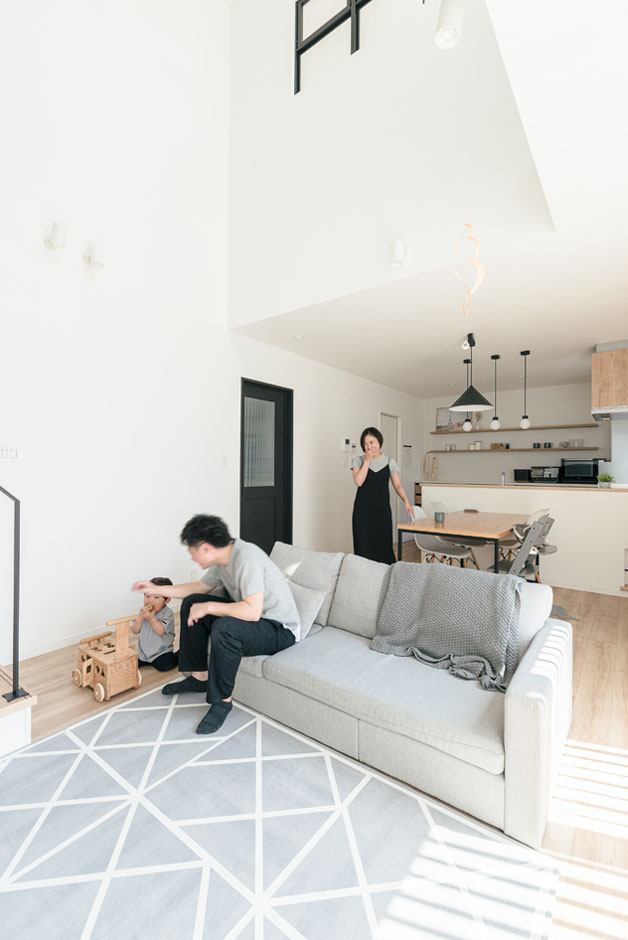 HAPPY HOUSE（山田工務店）【1000万円台、デザイン住宅、子育て】対面キッチンとリビング階段、それから大きな吹き抜けが家族を近づけ、自然なつながりが育まれていく。右手には宿題や事務作業にぴったりの造作カウンターが用意されている。大きな空間だが快適性は想像以上で、夏も冬も気持ちよく過ごせたそう