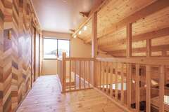 吹き抜けに面した２階のフリースペース。壁のクロスをアクセントに、木の空間を個性的に演出