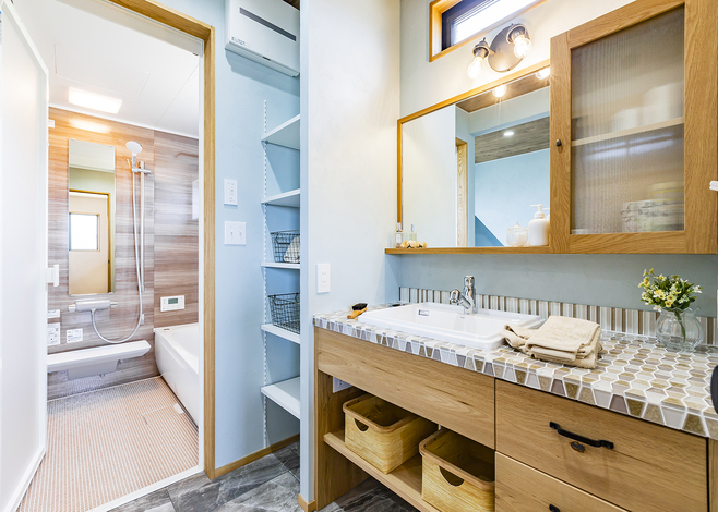 造作洗面台の天板には、ご主人が貼ったガラスタイルが輝く。鏡のサイズや扉付き収納、組み合わせた照明まで一つひとつこだわりが光る