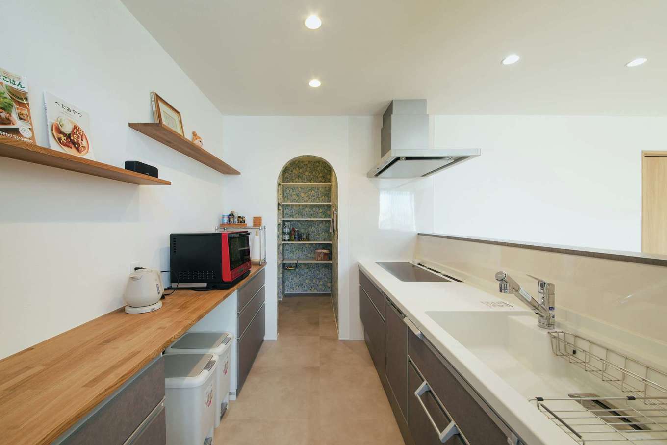 will建築工房【デザイン住宅、省エネ、間取り】キッチン背面は、カウンターとオープンラックで「見せる収納」スタイルに。キッチン奥には大容量のパントリーを用意し、入り口はアーチ型に仕上げた。内部の壁には奥さまのお気に入りのクロスを採用
