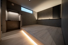 モダンな寝室。控えめな照明と、小上がりやデスクスペースといった機能的なデザインが、美しさを引き立てている。