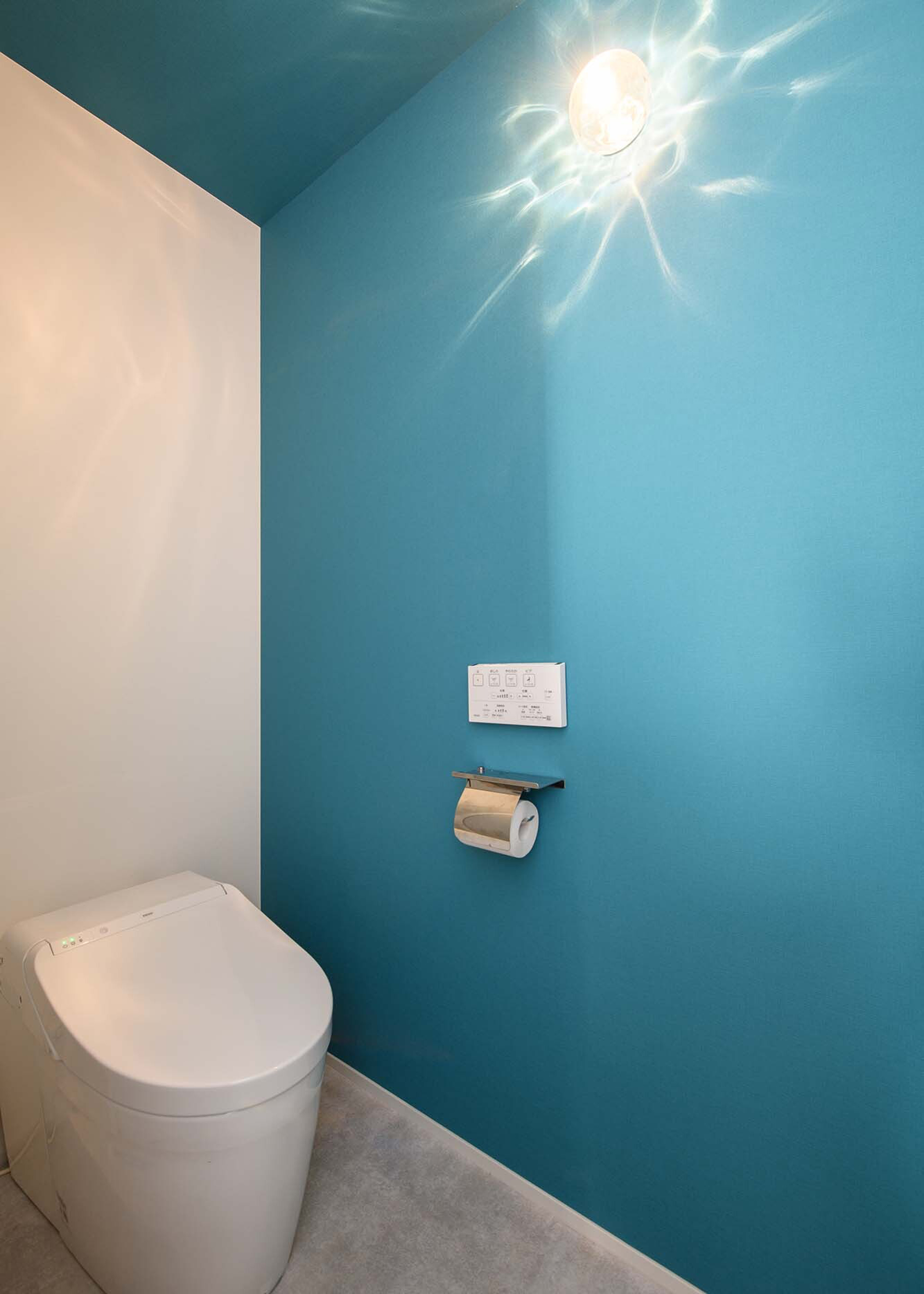平屋建築ブルーハウス【デザイン住宅、間取り、建築家】トイレは、鮮やかなマリンブルーのアクセントクロスや陰影が美しい照明などが提案され、奥さまこだわりのマリンテイストが実現。シンプル＆スタイリッシュでまとめた邸内に遊び心をプラスしている