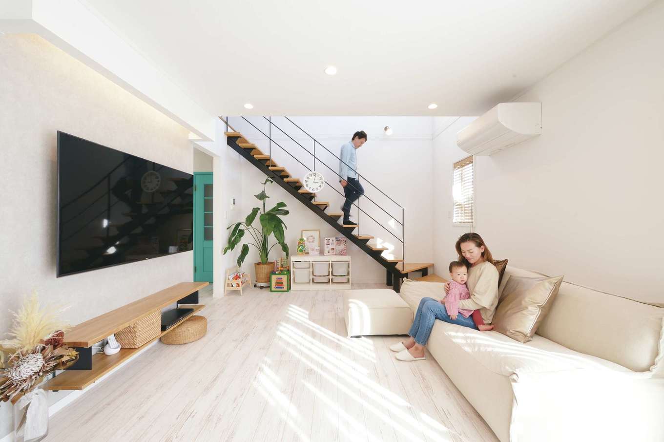 ハートホーム【子育て、輸入住宅、間取り】吹抜けと南面の窓からたっぷりの光が降り注ぐリビング。白を基調とした室内に黒いスチール階段、グリーンの建具が映える。シャビーなテイストのフローリングは床暖房仕様でほんのり暖かい