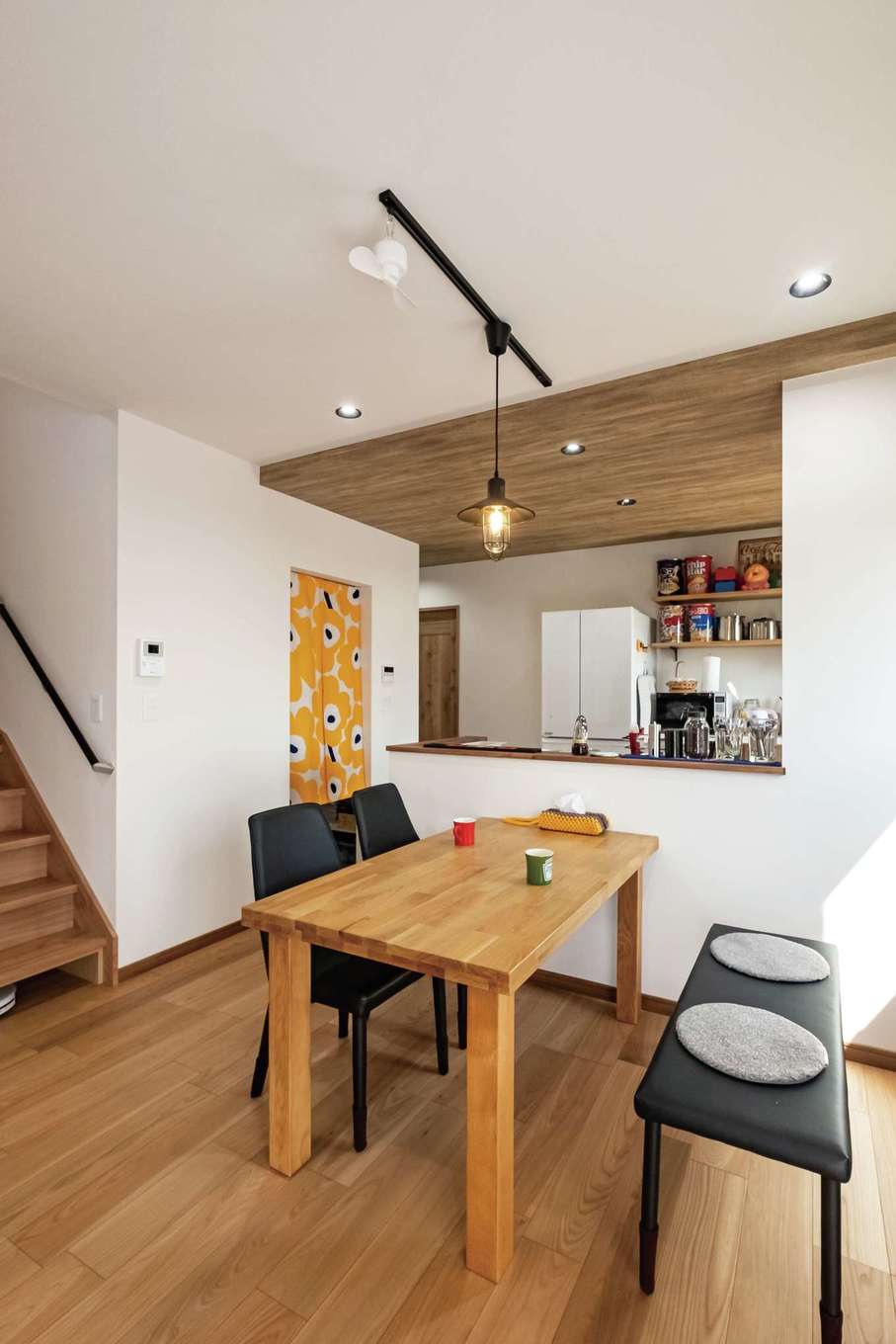 ぽっくハウス【リプルス】【デザイン住宅、収納力、趣味】キッチンは一段下げた木目の天井で役割を分けつつ、ぬくもりを添えた。階段下にロボット掃除機のお家を用意