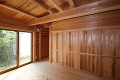 大きな窓と木製の内装が特徴の居室。外の景色を取り込みながら、温かみのある空間が心地よさを提供する。リラックスできる雰囲気が魅力的である。