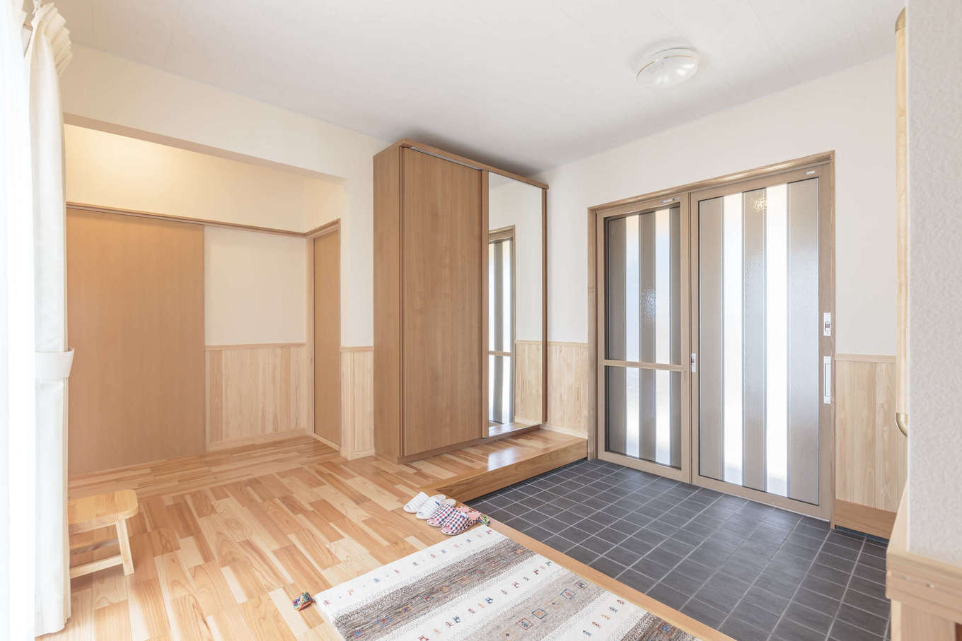 まちの大工さん 鈴木工務店【夫婦で暮らす、間取り、平屋】玄関は、土間とホールを広々と確保。玄関を中心に、プライベート空間とコミュニティ空間を左右に配置している。土間収納の扉には大きな姿見が付いていて、外出時に服装をチェックできる