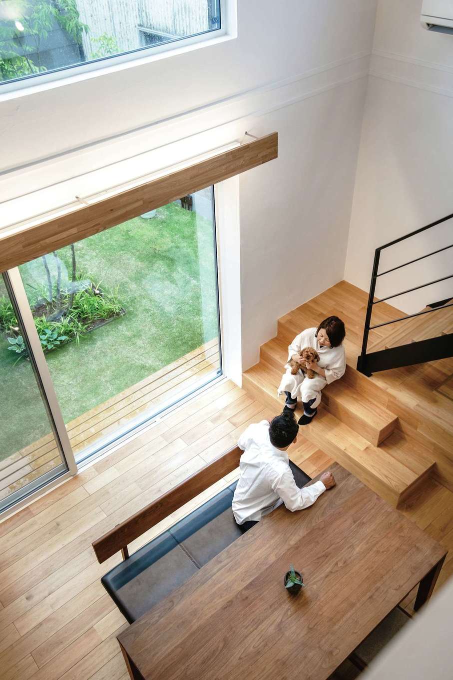 ainoa.life くらはし建築【デザイン住宅、間取り、インテリア】吹き抜けのダイニングで中庭を眺めながら、愛犬と一緒にひと休み。クルミの無垢の床の感触が心地よい。オリジナルの換気システムによって家の中の空気をクリーンに保ち、愛犬のニオイも気にならない