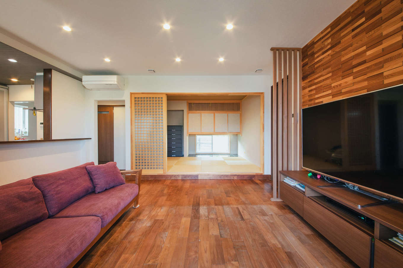 エフエフ住宅【子育て、和風、自然素材】チークの無垢板張りのアクセントウォールが高級感と重厚感をもたらすリビング。キッチンの正面に位置しているので、キッチンからもテレビを観たり、家族と会話したりできる