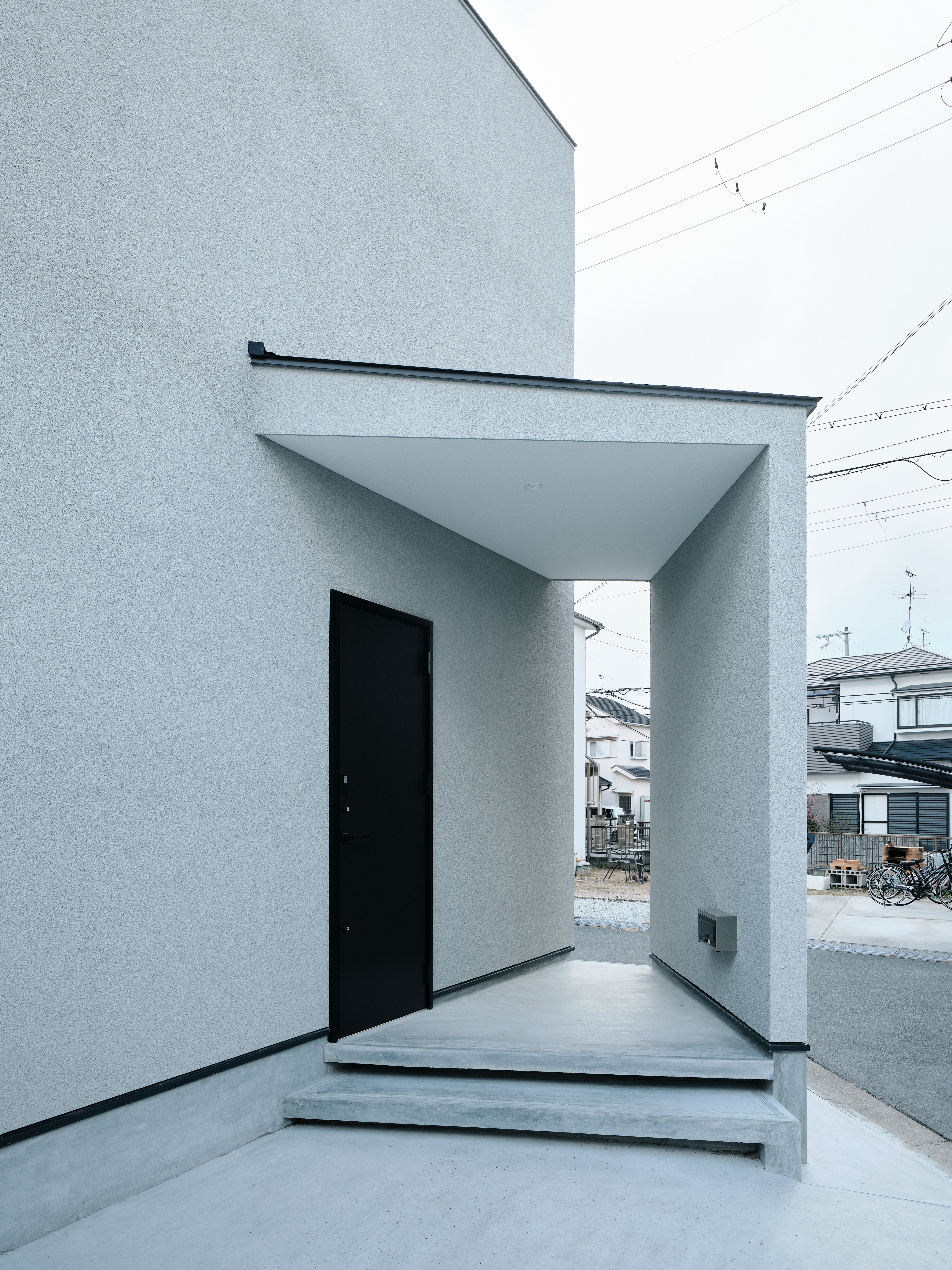K-rise｜ミニマルなデザインの外観。エントランスアプローチが直線的でシャープな印象を与え、都市部の洗練された雰囲気にマッチしている。