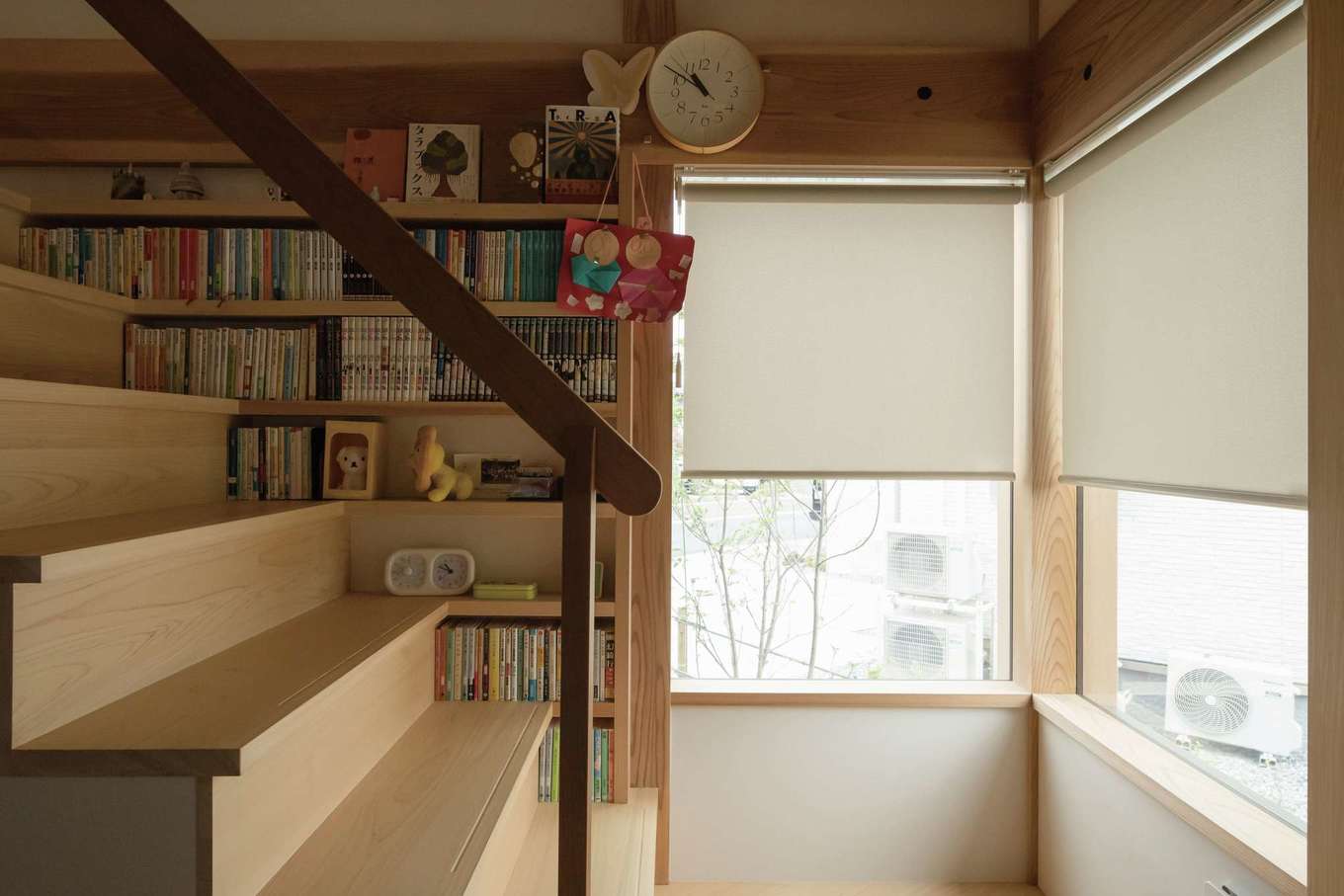 石牧建築【子育て、収納力、自然素材】FIX窓から優しい光が注ぐ階段。1段目の蹴込部には、お掃除ロボットが入るスペースも。段板の幅に合わせてつくられた文庫サイズの本がピッタリと入る