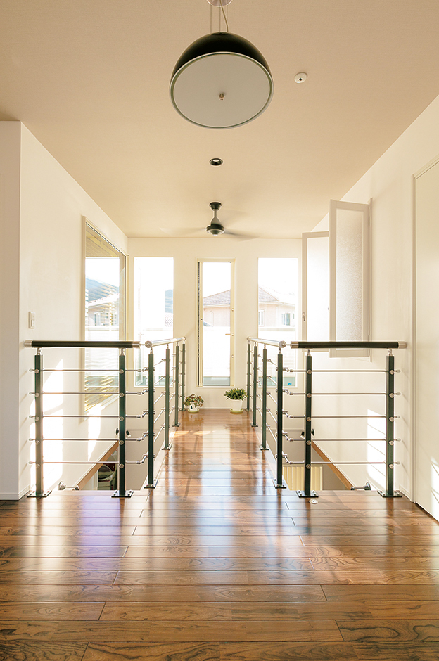 寝室や子ども部屋を通らずに洗濯物を干せるよう、フリースペースとバルコニーを空中廊下でつなげた。1階の暖かい空気が吹抜けを通して上がって来るので、2階のエアコンは使ったことがない。スタイリッシュなデザインの手すりは『納得』オリジナルのシムーラ