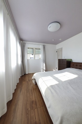 窓からたっぷりの自然光が降り注ぐ寝室。シンプルで落ち着いた内装が快適なリラックス空間を提供している