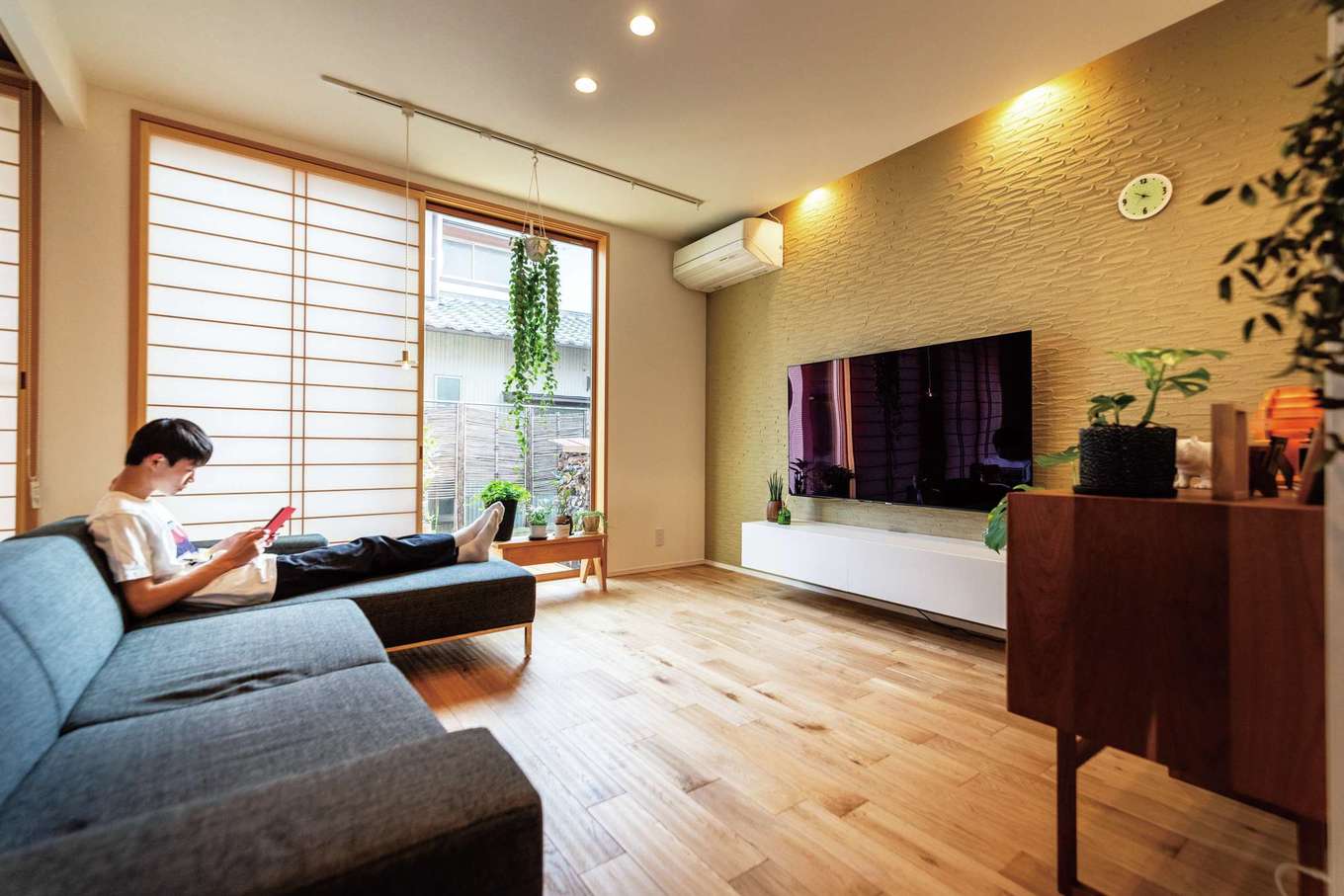 nattoku住宅【デザイン住宅、自然素材、間取り】土間リビング、和室、キッチンとゆるやかにゾーン分けされたセカンドリビング。テレビステーションの塗り壁は、調湿・消臭性に優れた「薩摩中霧島壁」を標準採用。テレビボード、L字型のソファも同社標準だ
