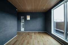 2階も無垢が敷かれ、壁には漆喰。寝室の壁は同社からの提案で、目も心も落ち着くブラックとした。左手にはたっぷりのハンガーラックを備える3畳のウォークインクローゼットを用意