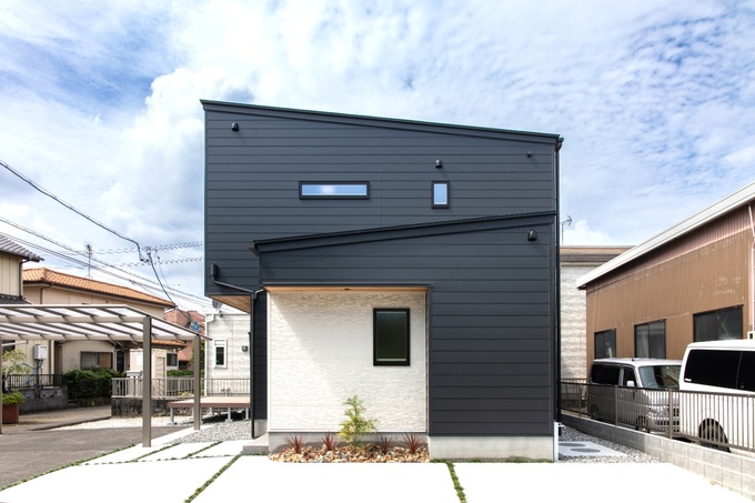 モダンなデザインの住宅外観。シンプルなラインが美しい外壁が特徴で、青空に見事に映えるシルエットが印象的である。