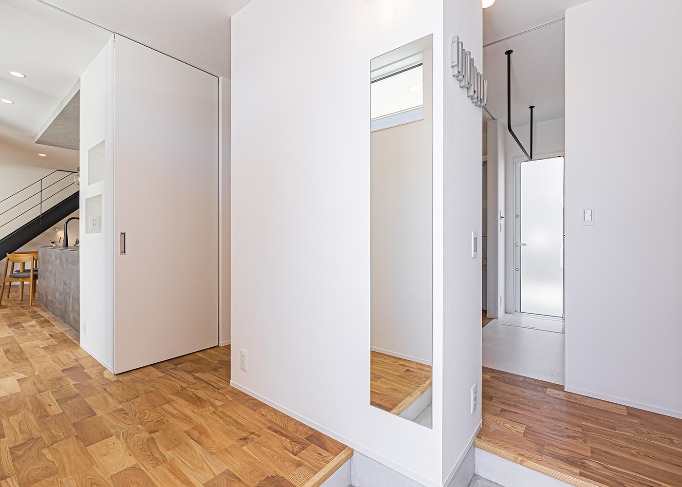 ARRCH アーチ【デザイン住宅、間取り、建築家】玄関にはLDK方向と水回り方向につながる2つの動線を確保。子どもが外から帰ってきたときに、泥だらけのまますぐランドリーに行くことができる