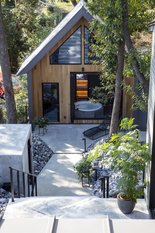 自然と調和する木製ファサードの建物外観。緩やかなアプローチが魅力で、周囲の緑が静かな雰囲気を演出している。ベランダで贅沢な時間が楽しめる。