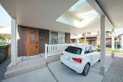 駐車場抱く大きなカバードポーチは、雨の日でもお子さまとの乗り降りや荷物の積み下ろしの負担を軽くする。一部に設けられたトップライトが、室内に明るさを運んでいる