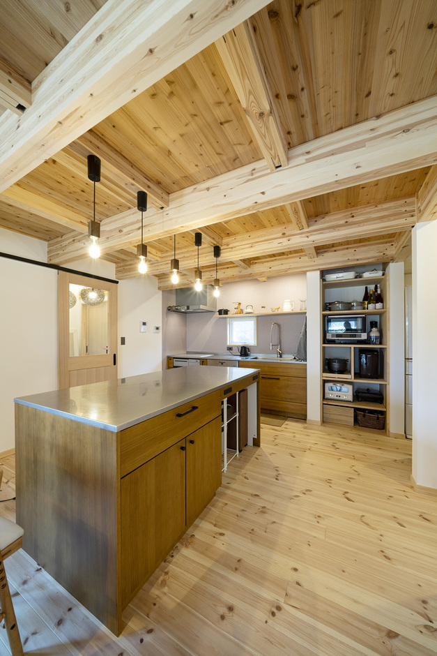 木の温もりを感じるウッドワンキッチン。天井と床の自然な木材の色合いが調和し、落ち着いた雰囲気を演出している
