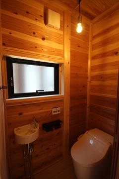 壁や天井に木材を使った温かみのあるトイレ。小さな窓から自然光が入り、居心地よい雰囲気を演出している。