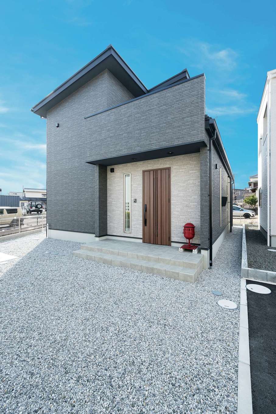 HAPPY HOUSE（山田工務店）【デザイン住宅、間取り、スキップフロア】外壁の色と質感にこだわったエッジの効いた外観。ファサードのサイディングと赤いポストがアクセントに。変形地を活かして広い庭もある