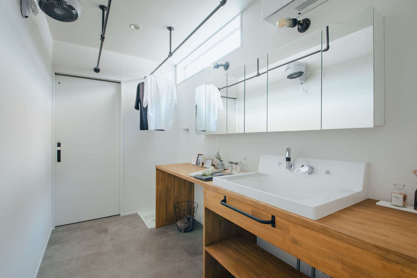 DAITOKU（大得工務店）【デザイン住宅、子育て、間取り】2階に設けたランドリールーム。壁付け式除湿機と物干しポールを設置して、外出している間に洗濯物がカラッと乾く。造作の洗面台は、美容関係の職業に就く奥さまの要望で、メイクもできるよう、長いカウンターとワイドな鏡を採用した
